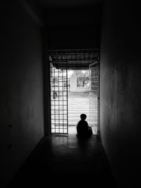Rear view of boy sitting at building entrance