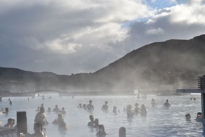 People swimming in pool against sky
