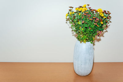 Close-up of flower vase on table against wall