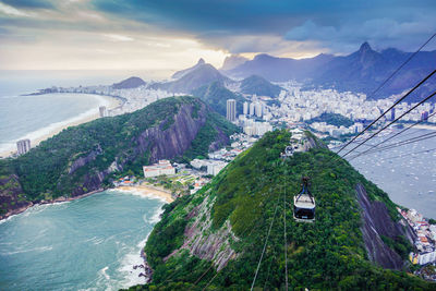 Overhead cable cars against land and seascape