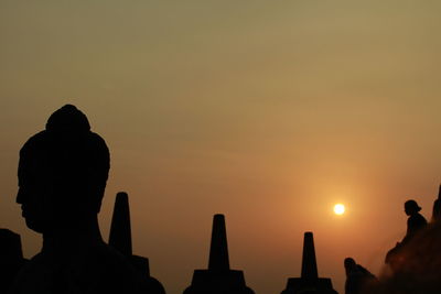 Silhouette buddha statue at borobudur temples during sunset