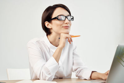 Young woman looking away while sitting on table