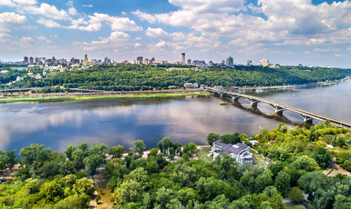 Scenic view of river by cityscape against sky