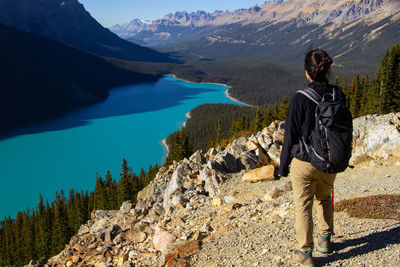 Rear view of man standing on rock by lake