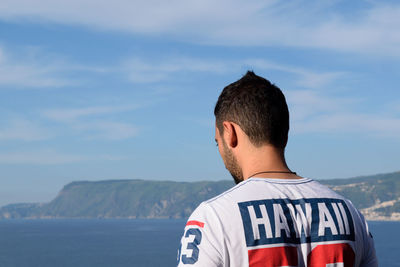 Rear view of man standing by sea against sky