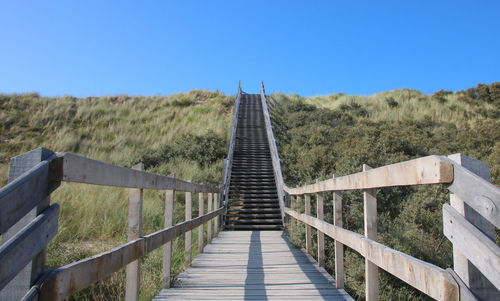 Footbridge at the beach against clear blue sky