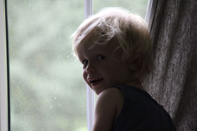 Portrait of cute boy by window at home