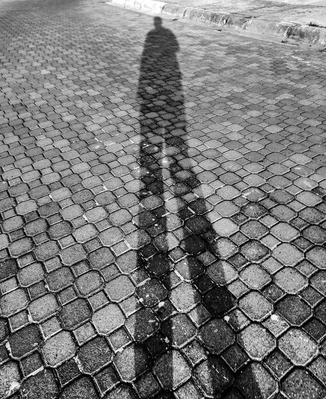 shadow, high angle view, real people, lifestyles, one person, street, city, day, leisure activity, focus on shadow, nature, sunlight, unrecognizable person, footpath, outdoors, transportation, paving stone, men, pattern