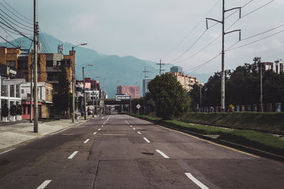 Road by buildings in city against sky