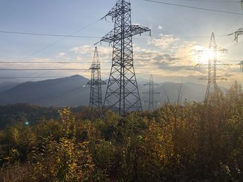 Low angle view of electricity pylon against sky during sunset