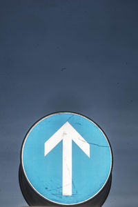 Close-up of road sign against blue sky