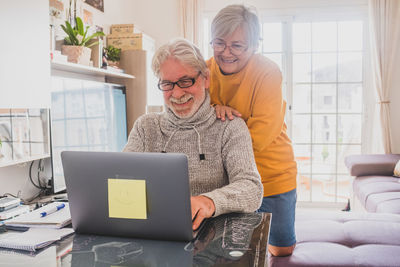 Woman by man using laptop at home