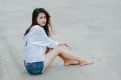 Young woman sitting on sand at beach