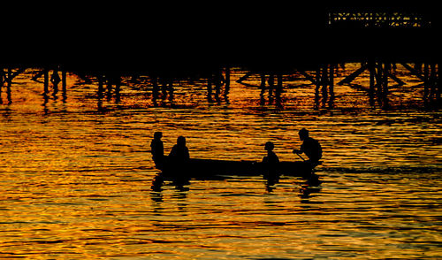 Silhouette people in lake against sky during sunset