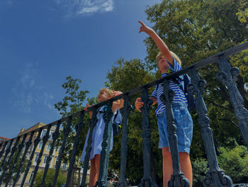 Low angle view of woman standing on footbridge against sky