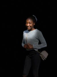 Portrait of smiling girl standing against black background