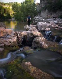 Man standing on rocks by river