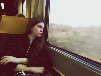 Thoughtful woman listening to music while traveling in train