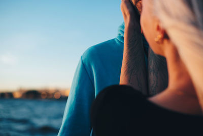 Woman embracing man against blue sky