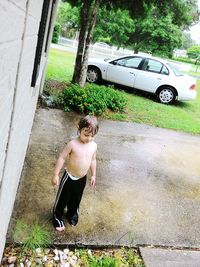 Full length of shirtless boy standing on tree