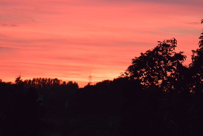 Silhouette trees against dramatic sky during sunset