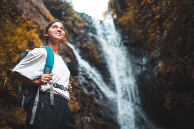 Young woman standing by waterfall