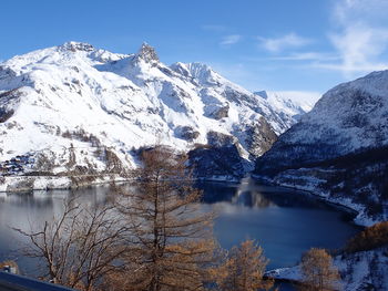 Scenic view of lake by snowcapped mountains against sky