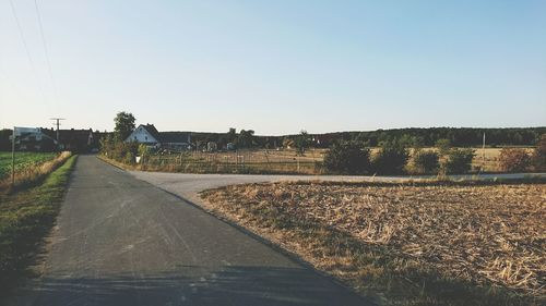 Road amidst field against clear sky