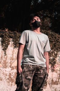 Young man wearing sunglasses standing against trees