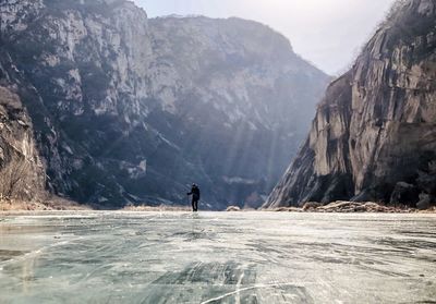 Man on frozen river in canyon 