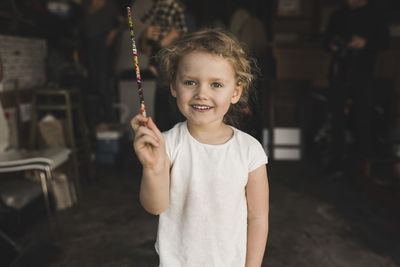 Portrait of girl showing magic wand in storage room