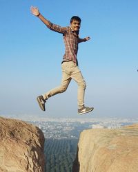 Full length of young man jumping against sky