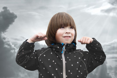 Close-up of cute girl standing against sky