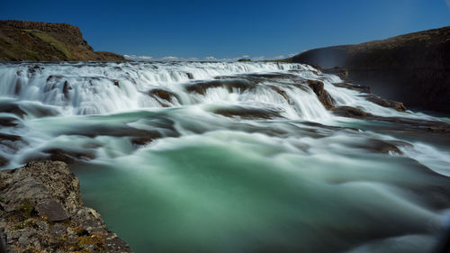 Scenic view of waterfall against sky
