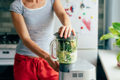 Midsection of woman holding ice cream at home