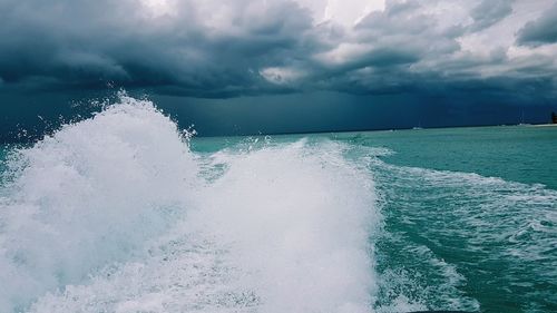 Waves splashing on sea against storm clouds