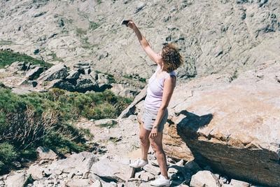 Full length of woman taking selfie on mountain during sunny day