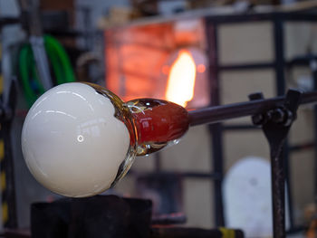 Artistic glassblower forms work of art at the end of glass pipe. shines a traditional glass furnace