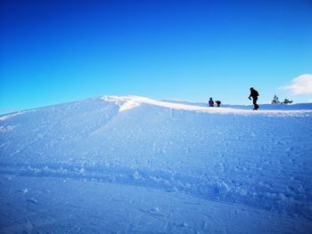 People on snowcapped mountain against clear blue sky