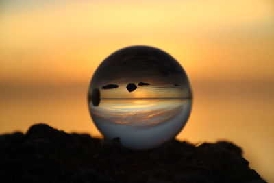Close-up of silhouette crystal ball against sky during sunset