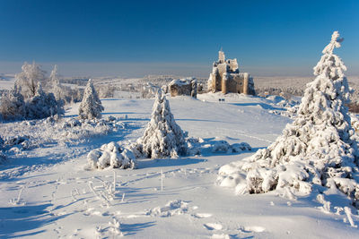 Snow covered landscape against clear blue sky