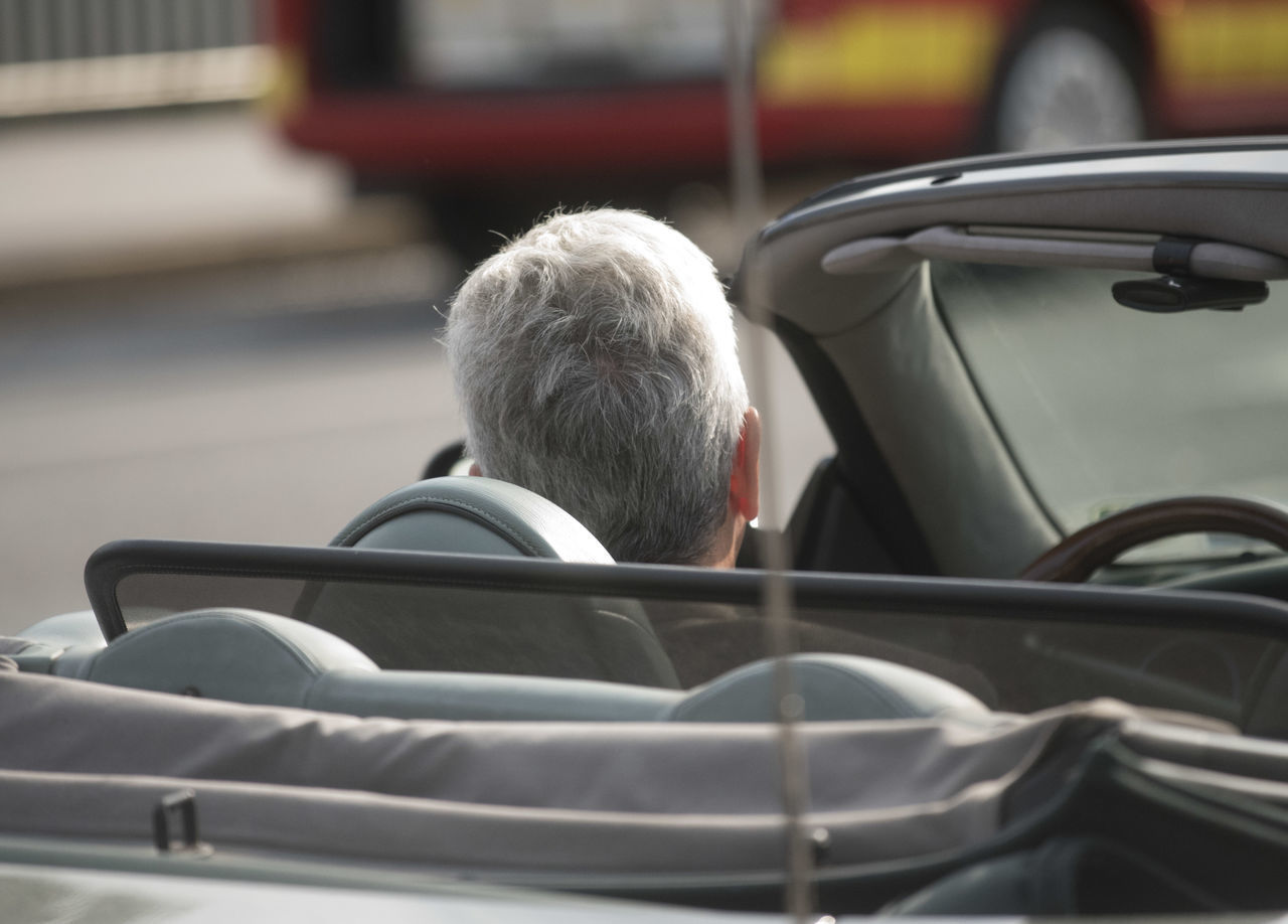 REAR VIEW PORTRAIT OF MAN SITTING ON CAR