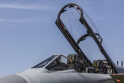 Fighter jet with open canopy against blue sky