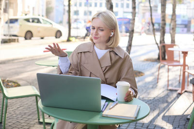 Young woman using laptop while sitting on table