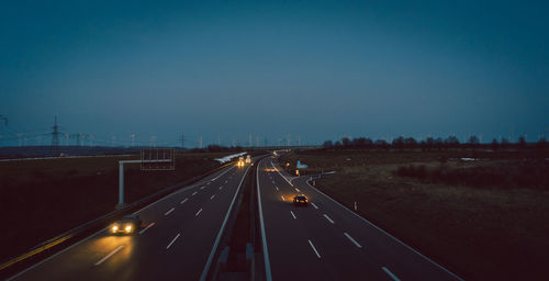 Cars moving on road against clear sky at night