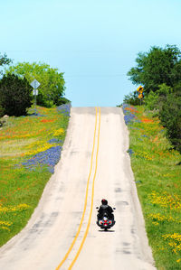 Man riding bicycle on road against sky