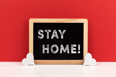 Close-up of information sign on table against red background