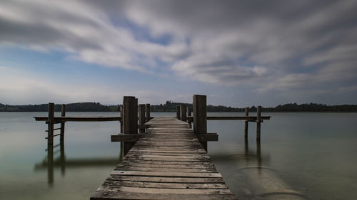 Wooden jetty on pier over lake against sky