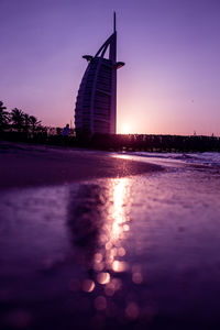 View of traditional windmill at lake during sunset