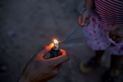 Midsection of man holding burning fire